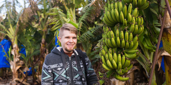 Smiling young woman looking away against trees