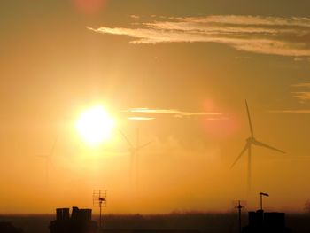 Silhouette of wind turbines against sunset sky