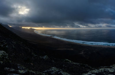 Scenic view of mountains by sea against sky during sunset