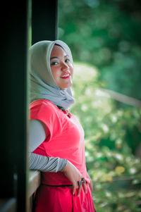 Portrait of young woman standing against plants