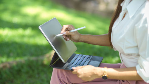 Midsection of woman using laptop at park