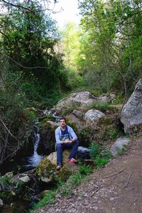 Full length of young woman sitting on tree