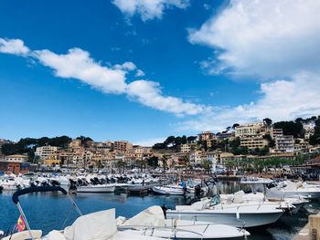 Sailboats moored in harbor against buildings in city