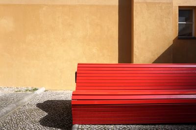 Empty red bench against wall