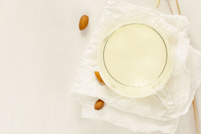 Glass cup of plant milk with almonds on a white background with copy space