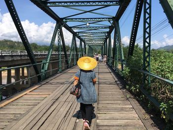 Rear view of woman walking on footbridge