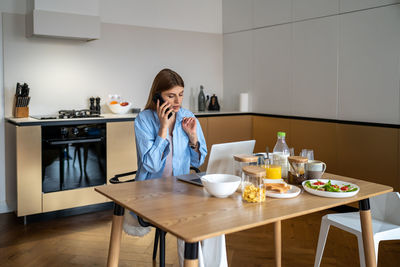 Portrait of young woman sitting on table at home