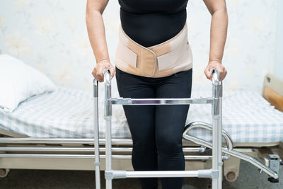 Low section of woman standing on bed