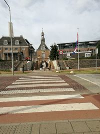 Road leading towards church against cloudy sky