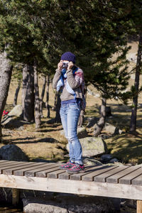 Rear view of girl standing against trees