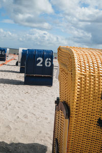 Hooded chairs on beach against sky