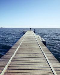 Pier over sea against clear blue sky