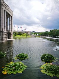 Scenic view of river by buildings against sky