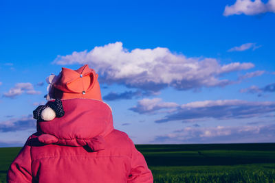 Rear view of person standing on agricultural field against sky