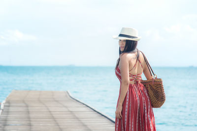 Young woman looking at sea against sky