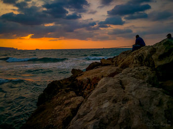 Rock formation on beach against sky during sunset