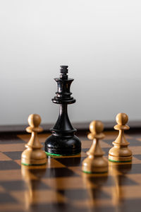 Close-up of game pieces on chess board against gray background