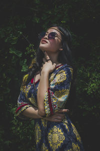 Beautiful young woman standing against plants