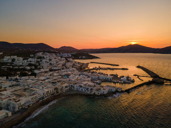 High angle view of townscape by sea against sky during sunset