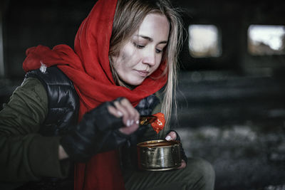 Close-up of young woman holding food sitting outdoors