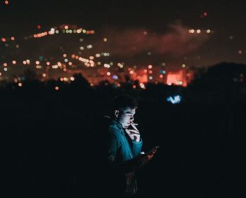 Man smoking while using phone in city at night