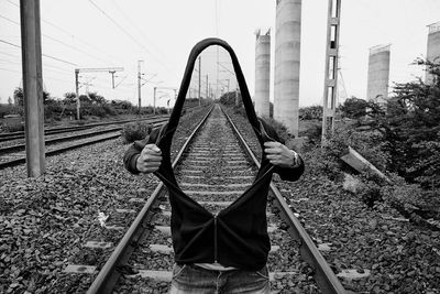 Rear view of man on railroad tracks against sky