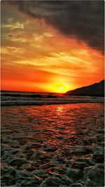 Scenic view of sea against dramatic sky during sunset