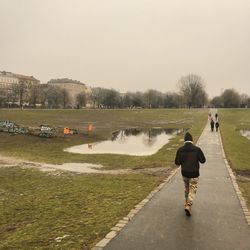 Rear view of woman walking on road against clear sky