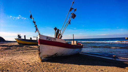 Fishing boats moored on beach against sky