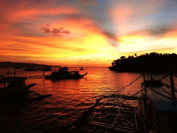 Silhouette boats moored on sea against orange sky