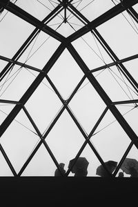 Low angle view of silhouette woman against sky seen through window