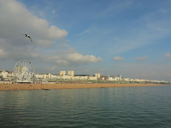 View of city at waterfront against cloudy sky