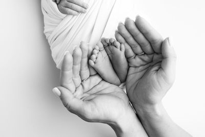 Cropped hand of woman holding hands against white background