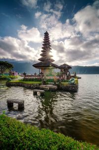 Traditional building by lake against sky