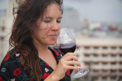 Close-up of woman drinking red wine in city