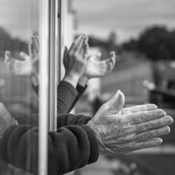 Close up of hands of a young woman and a old man clapping by the window