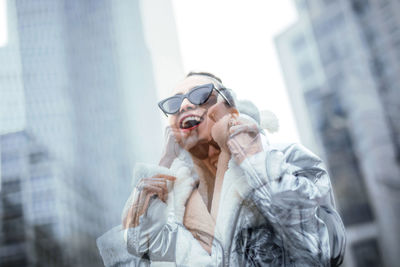 Blurred motion of cheerful woman wearing warm clothing in city