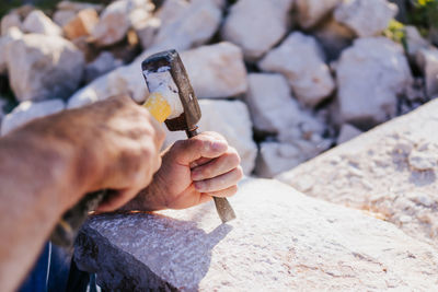 Cropped hands of person carving on rock