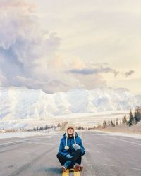 Portrait of woman sitting on road against mountain