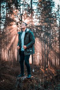 Man standing by trees in forest