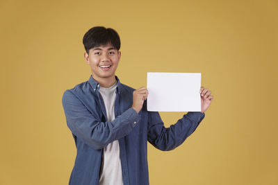 Portrait of a smiling young man against yellow background