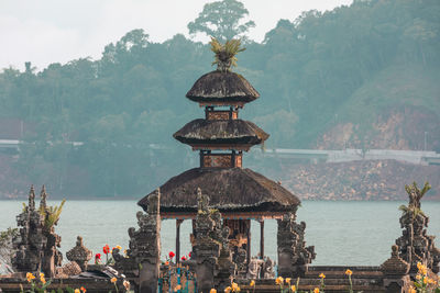 View of ancient temple by lake against trees