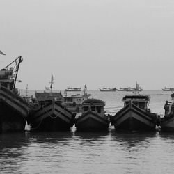 Boats moored in sea against clear sky