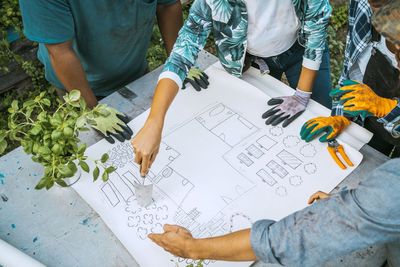 High angle view of male and female farmers examining blueprint in farm