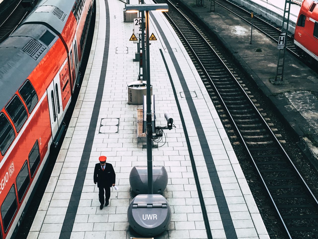 rail transportation, transportation, railroad station, mode of transportation, real people, public transportation, track, railroad track, railroad station platform, men, high angle view, travel, one person, lifestyles, architecture, train, train - vehicle, luggage, passenger, outdoors, waiting, station, arrival