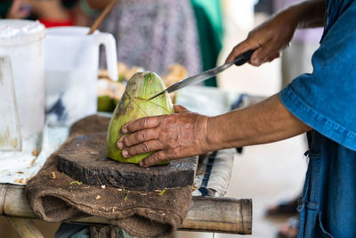 Midsection of man cutting coconut fruit