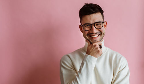 Portrait of young man wearing sunglasses while standing against wall
