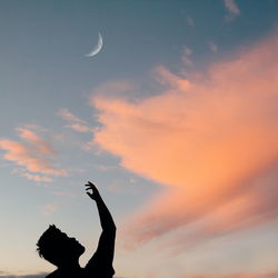 Low angle view of silhouette man gesturing against sky during sunset