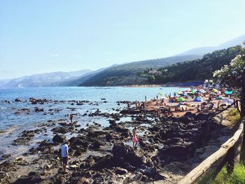 People at beach against clear sky