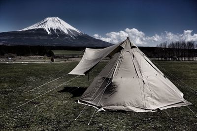 Tent on field by mountain against sky